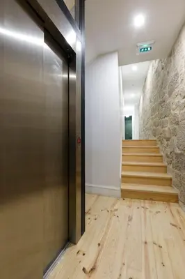 a hallway with a staircase and a door with wooden floors at Oporto Cosy Apartment in Porto