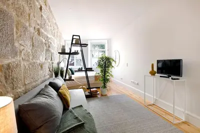 a living room with a couch and a stone wall at Oporto Lovely Apartment in Porto