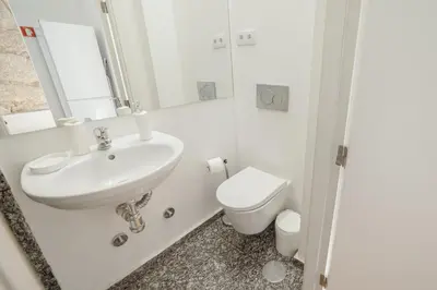 a white bathroom with a sink and a toilet at Constituição Deluxe by Hosty in Porto