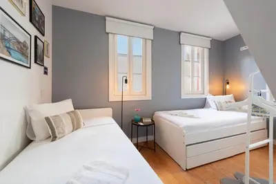 two beds in a small room with two windows at Mouzinho Rooftop View in Porto
