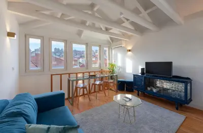 a living room with a blue couch and a tv at Mouzinho Rooftop View in Porto
