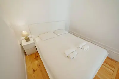 a small white room with two towels on a bed at Cozy Almada by Hosty in Porto