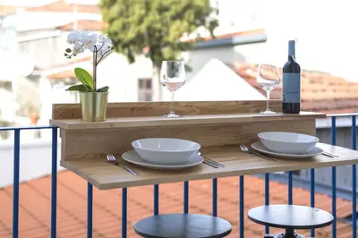 a wooden table with two glasses and bowls and plates on a balcony at S. Bento Downtown Apt in Porto