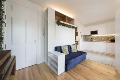 a living room with a blue couch and a white wall at S. Bento Downtown Apt in Porto