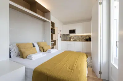 a white room with a bed and a kitchen at S. Bento Downtown Apt in Porto