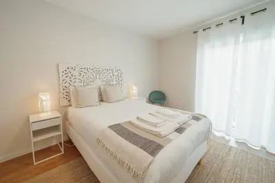 a white bedroom with a large white bed with a window at Morro Garden Apartment by Hosty in Vila Nova de Gaia