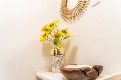 a vase with yellow flowers and a mirror on a shelf at Morro Garden Apartment by Hosty in Vila Nova de Gaia