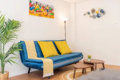 a blue couch with yellow pillows in a living room at Morro Garden Apartment by Hosty in Vila Nova de Gaia