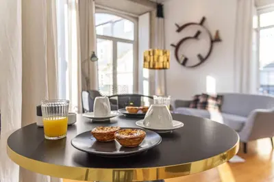 a table with three donuts and a glass of orange juice at Mouzinho Penthouse by Hosty in Porto