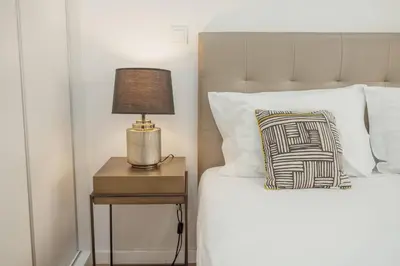 a bed with a side table with a lamp on it at Coliseu Apartment by Hosty in Porto