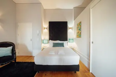 a bedroom with a large white bed and a chair at OPORTO GUEST Luxus Garden in Porto