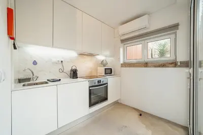 a kitchen with white cabinets and a sink and a window at OPORTO GUEST Luxus Garden in Porto