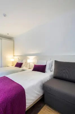 two beds in a room with purple sheets and pillows at PATH Bonjardim Apartments in Porto