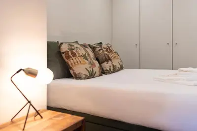 a white bed with a lamp and a pillow on it at Exotic Flat with Shared Pool & Garden in Porto