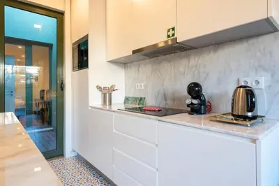 a kitchen with white cabinets and a counter top at Exotic Flat with Shared Pool & Garden in Porto