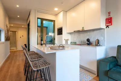 a kitchen and living room with a counter and stools at Exotic Flat with Shared Pool & Garden in Porto