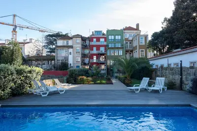 a swimming pool with chairs and a group of buildings at Exotic Flat with Shared Pool & Garden in Porto