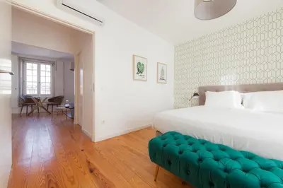 a bedroom with a white bed and a green bench at Citybreak-apartments Sao Bento in Porto