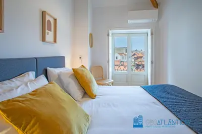 a bedroom with a bed with white sheets and yellow pillows at Poveiros Oak Loft - Santo Ildefonso in Porto