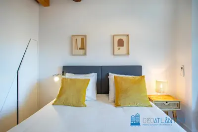 a white bed with two yellow pillows on it at Poveiros Oak Loft - Santo Ildefonso in Porto