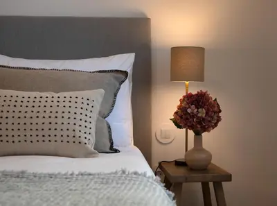 a bed with a lamp and a vase of flowers on a table at Quadra Apartment - Luxury & Relaxation in Porto