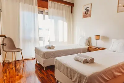a hotel room with two beds and a window at Apartamento Santos Pousada 2 in Porto