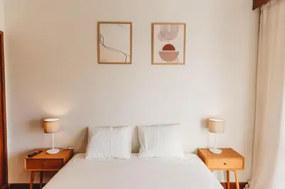 a bedroom with a white bed with two nightstands and two lamps at Apartamento Santos Pousada 2 in Porto