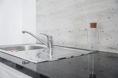 a kitchen sink with a glass bottle on a counter at PortoNest Downtown Suites in Porto