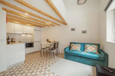 a living room with a blue couch and a kitchen at Lapa Cozy by Hosty in Porto