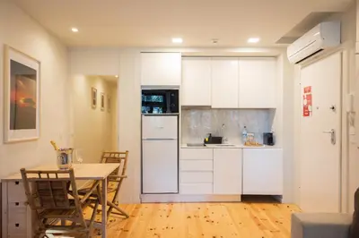 a kitchen with a table and a white refrigerator at Cosy House Downtown Porto with swimming pool and AC in Porto