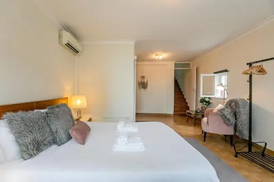 a bedroom with a white bed and a chair at Stunning Clerigos Duplex apartment in the heart of Porto in Porto