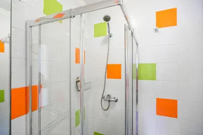 a shower with orange and green squares on the wall at Clerigos Studio Apts in Porto