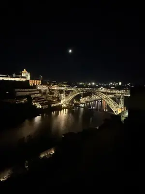 a bridge over a river at night with the moon at Casa Astória - City Centre Historical Building with Amazing River View in Porto