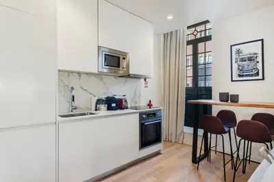 a kitchen with white cabinets and a table with chairs at GuestReady - A secret passage in Porto in Porto