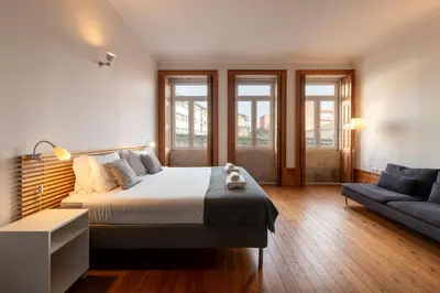 a bedroom with a large bed and a couch at Fontainhas Flat: Balcony & Parking in Porto