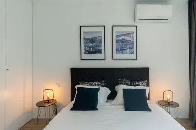 a bedroom with a white bed with three pictures on the wall at GuestReady - Oporto Blue Douro Residence in Porto
