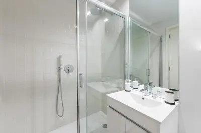a white bathroom with a shower and a sink at Frei Yellow Studio in Porto