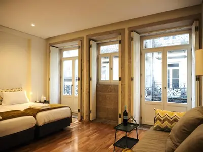 a bedroom with a bed and a couch and windows at ALMARELA apartments in Porto