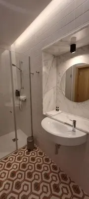 a bathroom with a sink and a shower and a mirror at ALMARELA apartments in Porto