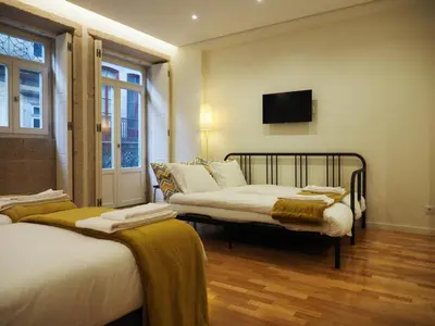 a bedroom with two beds and a tv on the wall at ALMARELA apartments in Porto