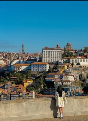 a woman standing on a wall looking at a city at Porto Bello - Apartamento - 3 in Porto