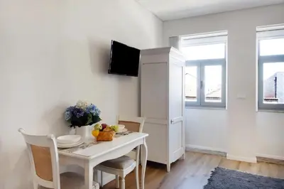 a white dining room with a table and a refrigerator at Porto Bello - Apartamento - 5 in Porto