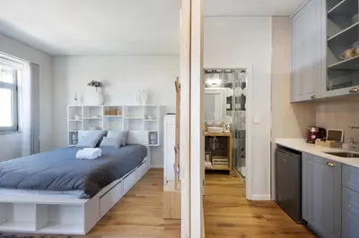 a bedroom with a large bed and a kitchen at Porto Bello - Apartamento - 5 in Porto