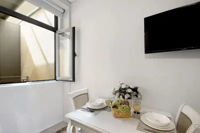a white dining room with a table and a tv at Porto Bello - Apartamento - 6 in Porto