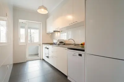 a white kitchen with white cabinets and a sink at Host Wise - Spacious Modern Flat w Balcony in Porto