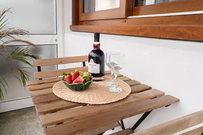 a bottle of wine and a bowl of fruit on a table at Host Wise - Spacious Modern Flat w Balcony in Porto