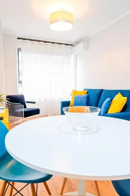 a living room with a white table and blue couch at Emotions Trindade Flat in Porto