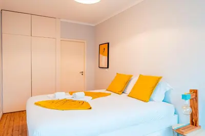 a bedroom with a large white bed with yellow pillows at Emotions Trindade Flat in Porto