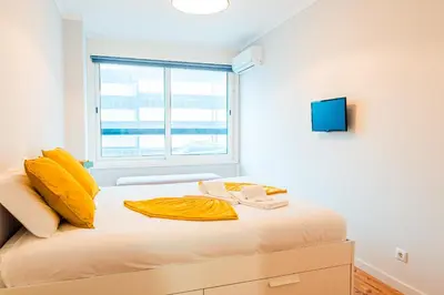 a bedroom with a bed with yellow sheets and a window at Emotions Trindade Flat in Porto