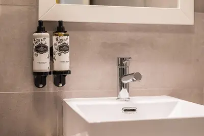two bottles of wine are on a bathroom sink at Golden Factory Apartment Downtown, Terrace and AC in Porto